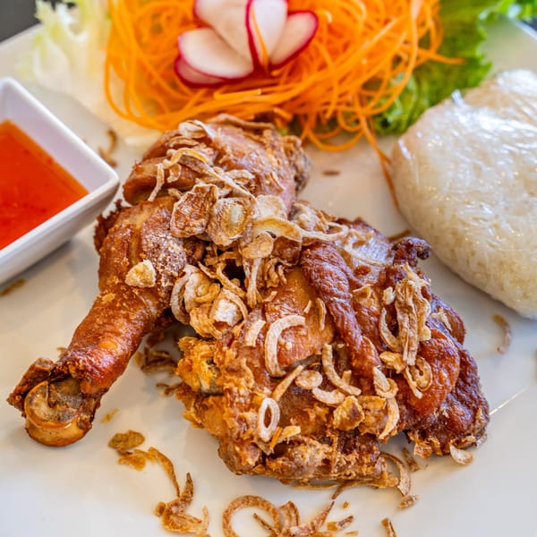 Crispy fried chicken with fried shallots, sticky rice, sweet chili sauce, and shredded carrots.